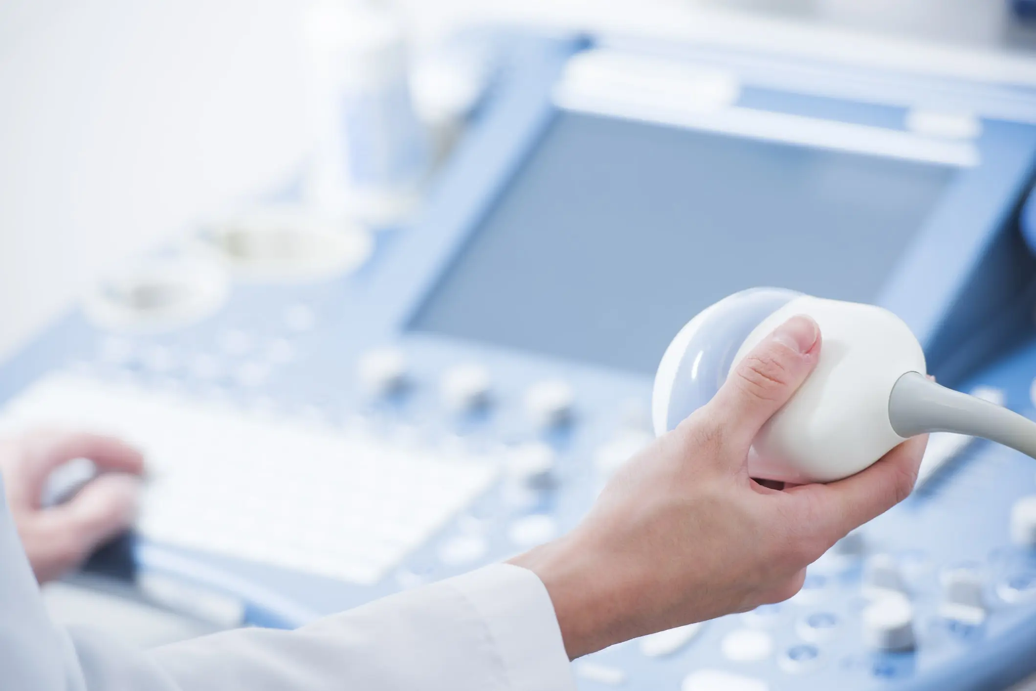 Medical illustration showing a hand holding an ultrasound machine