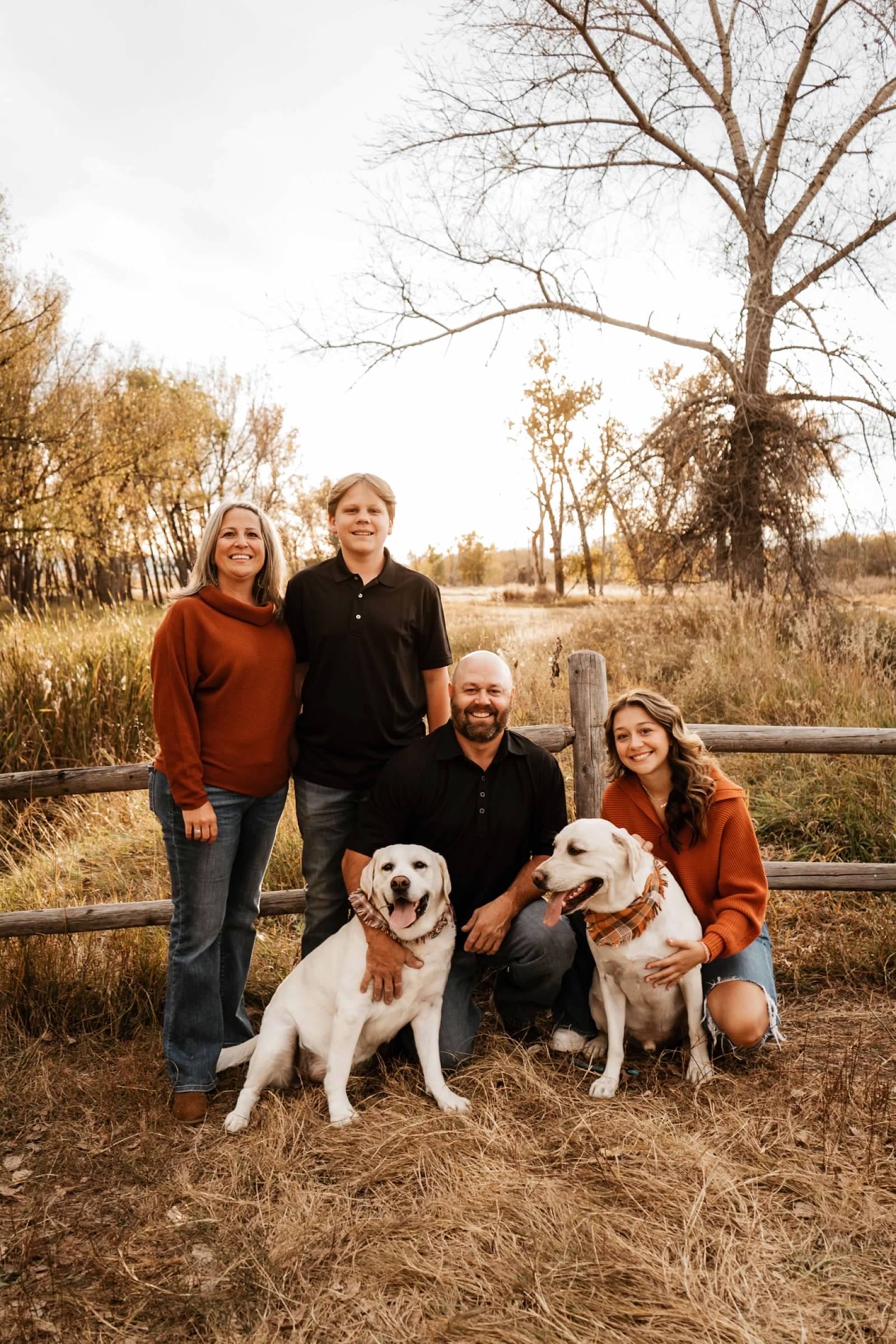 radiologic technician, Kristin Miller, stands with her family and two dogs, outdoors.